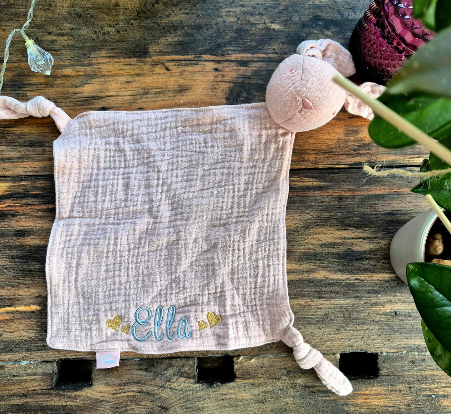Ein weiches, personalisierbares Schmusetuch in Form eines Hasen, aus feinem Musselinstoff. Das Tuch ist in sanften Pastellfarben gehalten und bietet eine bestickte Fläche für individuellen Namen oder Botschaften. Die Ohren des Hasen sind lang und flauschig, ideal für kleine Kinderhände zum Greifen und Kuscheln.