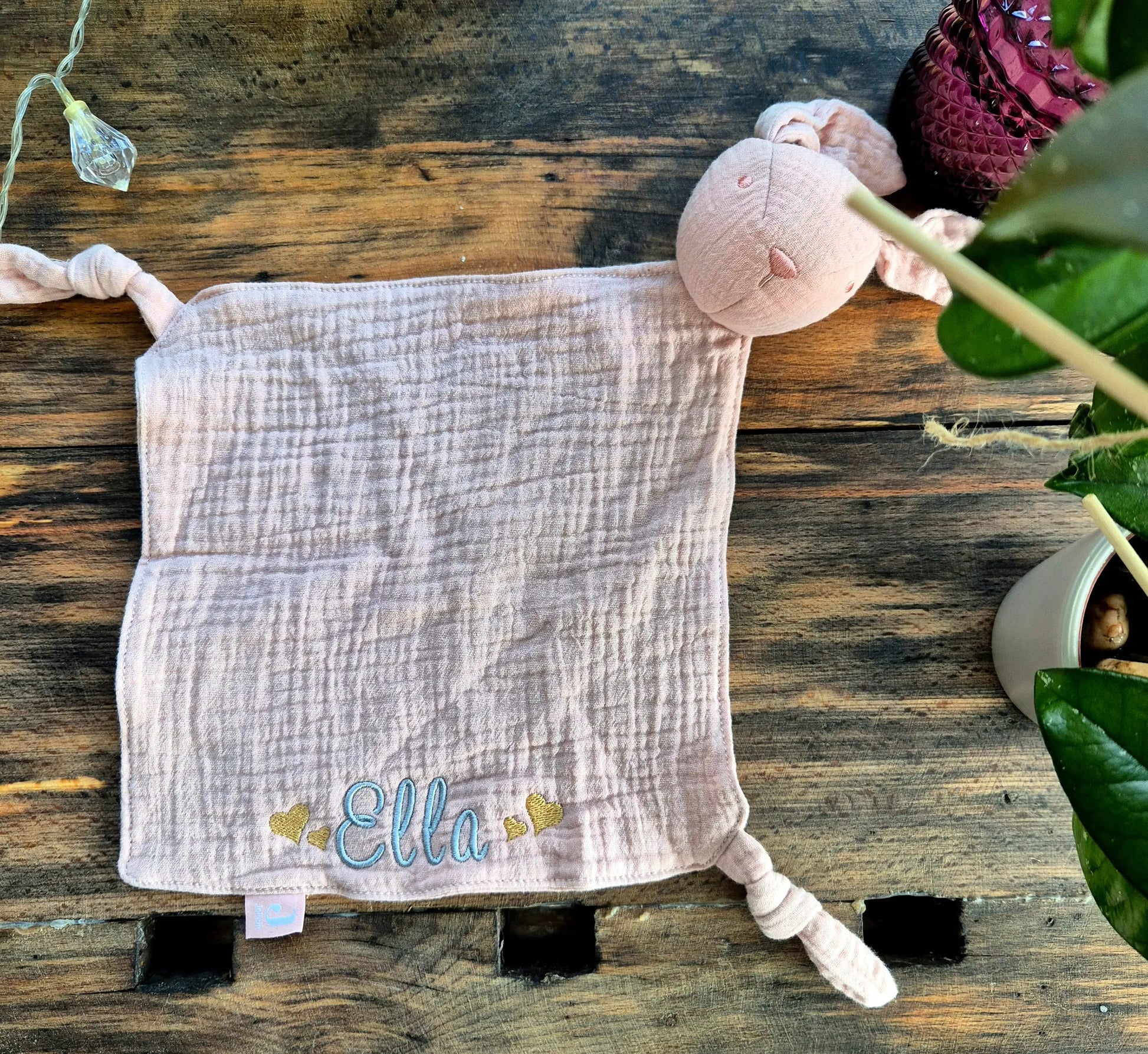 Ein weiches, personalisierbares Schmusetuch in Form eines Hasen, aus feinem Musselinstoff. Das Tuch ist in sanften Pastellfarben gehalten und bietet eine bestickte Fläche für individuellen Namen oder Botschaften. Die Ohren des Hasen sind lang und flauschig, ideal für kleine Kinderhände zum Greifen und Kuscheln.